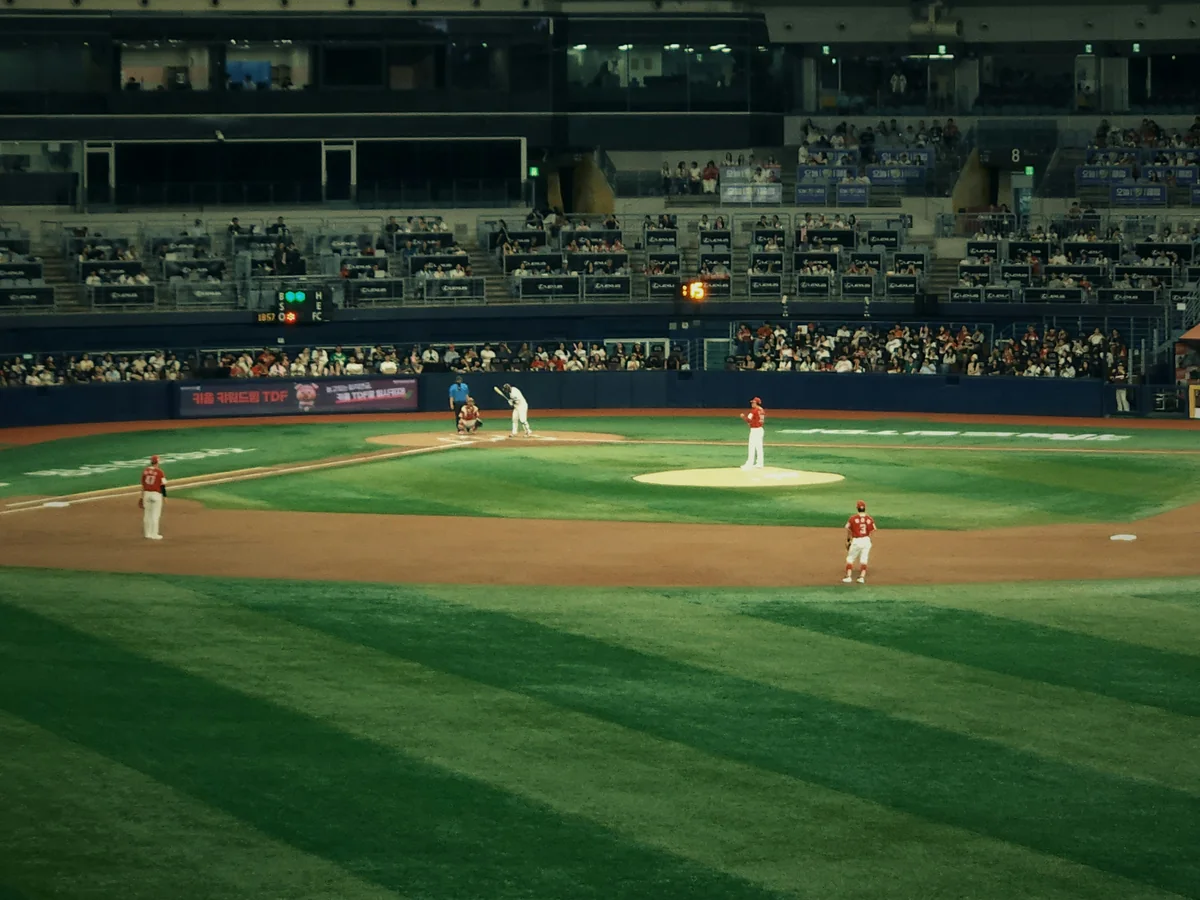 A batter at the plate during a night KBO game, with a packed, lit stadium behind him